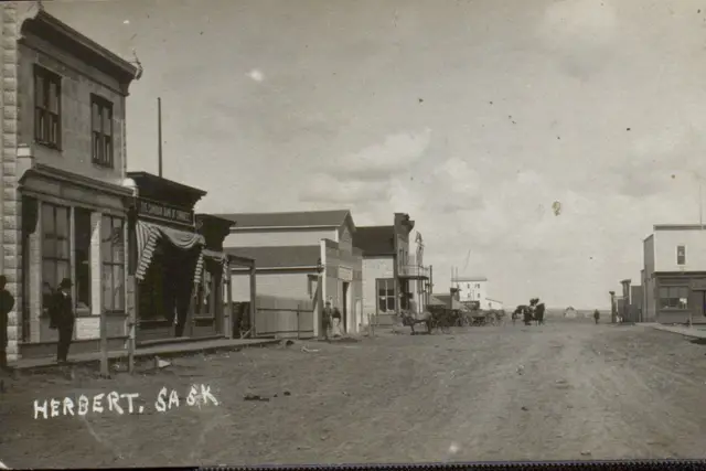Street scene with storefronts and wagons, Herbert